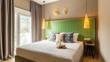 Een slaapkamer met een groot bed, een groen hoofdeinde, twee wandlampen en een klein nachtkastje met een plant.