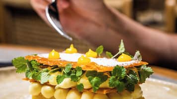 A dessert with mint leaves and yellow elements on a plate.