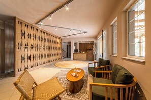 A modern interior with a wooden wall panel, a round coffee table, and seating area. - Skiathos Theros (Skiathos)