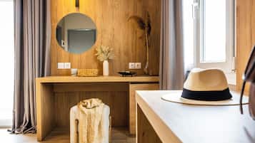 Un tocador de madera con un espejo redondo, un florero con plantas secas y un sombrero sobre una mesa.