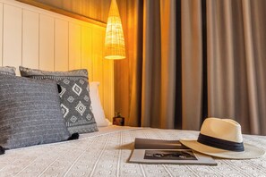A neatly made bed with patterned pillows, a hat, and a book on a textured bedspread. - Skiathos Theros (Skiathos)
