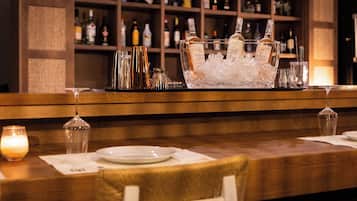 Een bar met een houten toonbank, een ijs gevulde glazen container en verschillende flessen.
