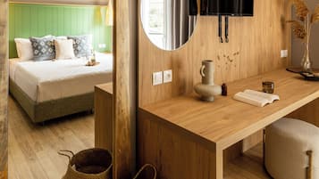 A modern room with a wooden desk, a mirror, a bed with green headboard, and a mounted TV.