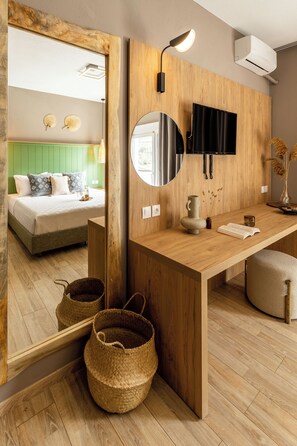 A modern room with a wooden desk, a mirror, a bed with green headboard, and a mounted TV. - Skiathos Theros (Skiathos)