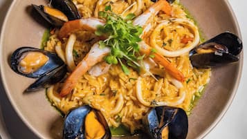Une assiette de pâtes aux fruits de mer, avec des moules et des crevettes, garnie de verdure.