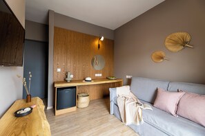 Ein modernes Wohnzimmer mit einer Wand in Holzoptik, einem grauen Sofa und einem kleinen Holztisch mit einer Schüssel und einem Hut.