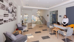 A modern hotel lobby with a reception desk, seating area, and a staircase leading to upper floors. - Naama Bay Suites & Spa - Sharm (Sharm El Sheikh)