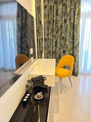 A modern room with a glass table, a black coffee machine, a yellow chair, and patterned curtains. - Naama Bay Suites & Spa - Sharm (Sharm El Sheikh)