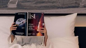 A person lying on a bed with a magazine, a tray of breakfast, and a large rock wall behind. - Radisson Blu Hotel Riyadh Convention & Exhibition Center (Riyadh)