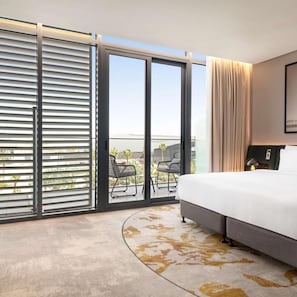 A hotel room with a large bed, a view of the outdoors, and a balcony with chairs. - Radisson Blu Hotel Riyadh Convention & Exhibition Center (Riyadh)