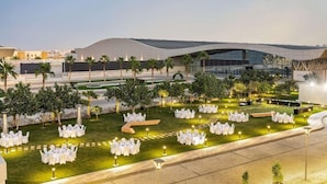 A modern building with a curved roof and a well-lit outdoor area with white tables and chairs arranged for an event. - Radisson Blu Hotel Riyadh Convention & Exhibition Center (Riyadh)