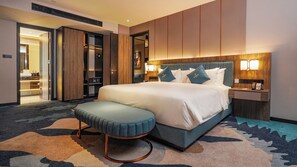 A hotel room with a large bed, a bedside table with a lamp, a wardrobe, and a bathroom visible through an open door. - Fugo Hotel Samarinda (Samarinda)
