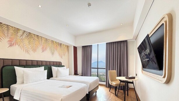 A hotel room with two beds, a TV, a chair, and a large window with a view.
