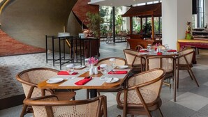 Un restaurante moderno con mesas redondas, sillas de mimbre y lámparas colgantes.