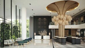 A modern lobby with a central reception desk, seating areas, and a distinctive ceiling light fixture.