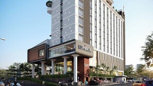 A modern hotel with a prominent 'LUXMINOR' sign, featuring a multi-story structure with a flat roof and a mix of glass and brick facade.