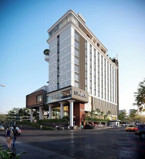Un hotel moderno con un llamativo letrero 'LUXMINOR', que presenta una estructura de varios pisos con techo plano y fachada de vidrio y ladrillo.