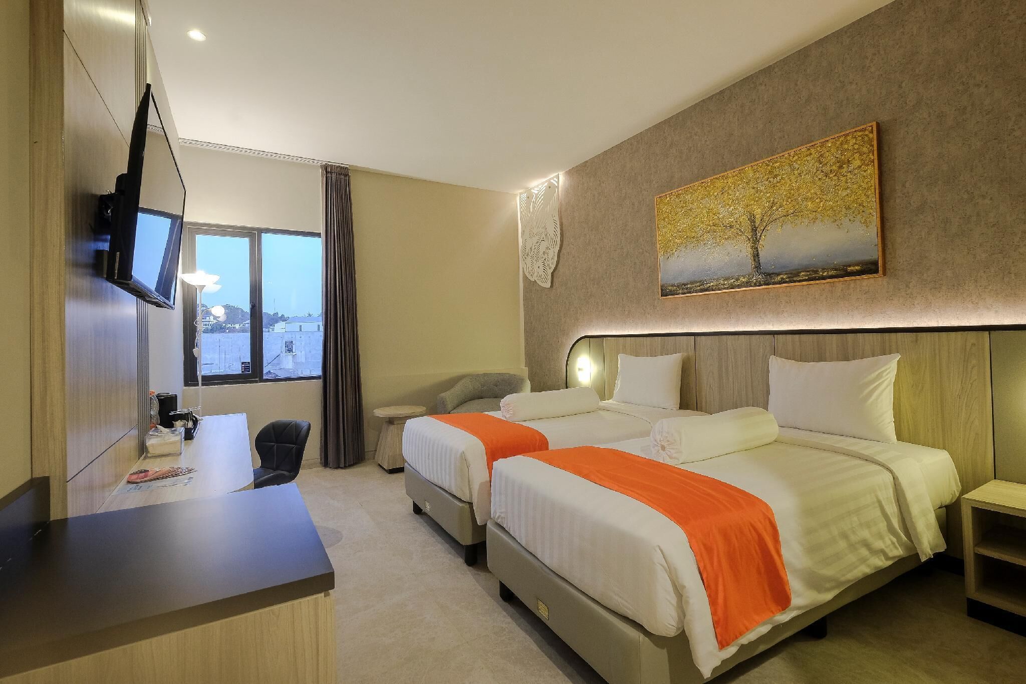 Una habitación de hotel con dos camas, un escritorio, un televisor y un cuadro en la pared.