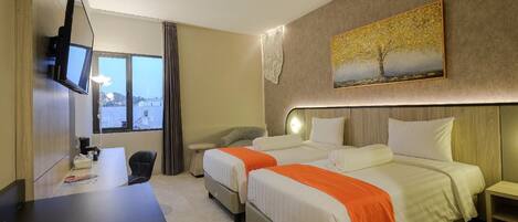 Una habitación de hotel con dos camas, un escritorio, un televisor y un cuadro en la pared.