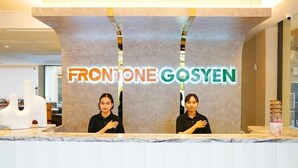 Una recepción con el letrero "FRONTONE GOSYEN" y dos empleados detrás.