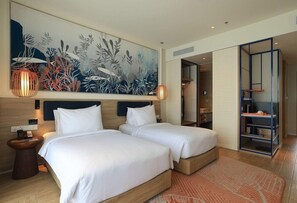 Une chambre d’hôtel avec deux lits, une grande peinture abstraite, une tête de lit en bois, une table de chevet, une lampe et une vue sur la pièce.