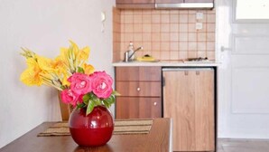 A kitchen with wooden cabinets, a tiled backsplash, and a red vase with flowers on a table.