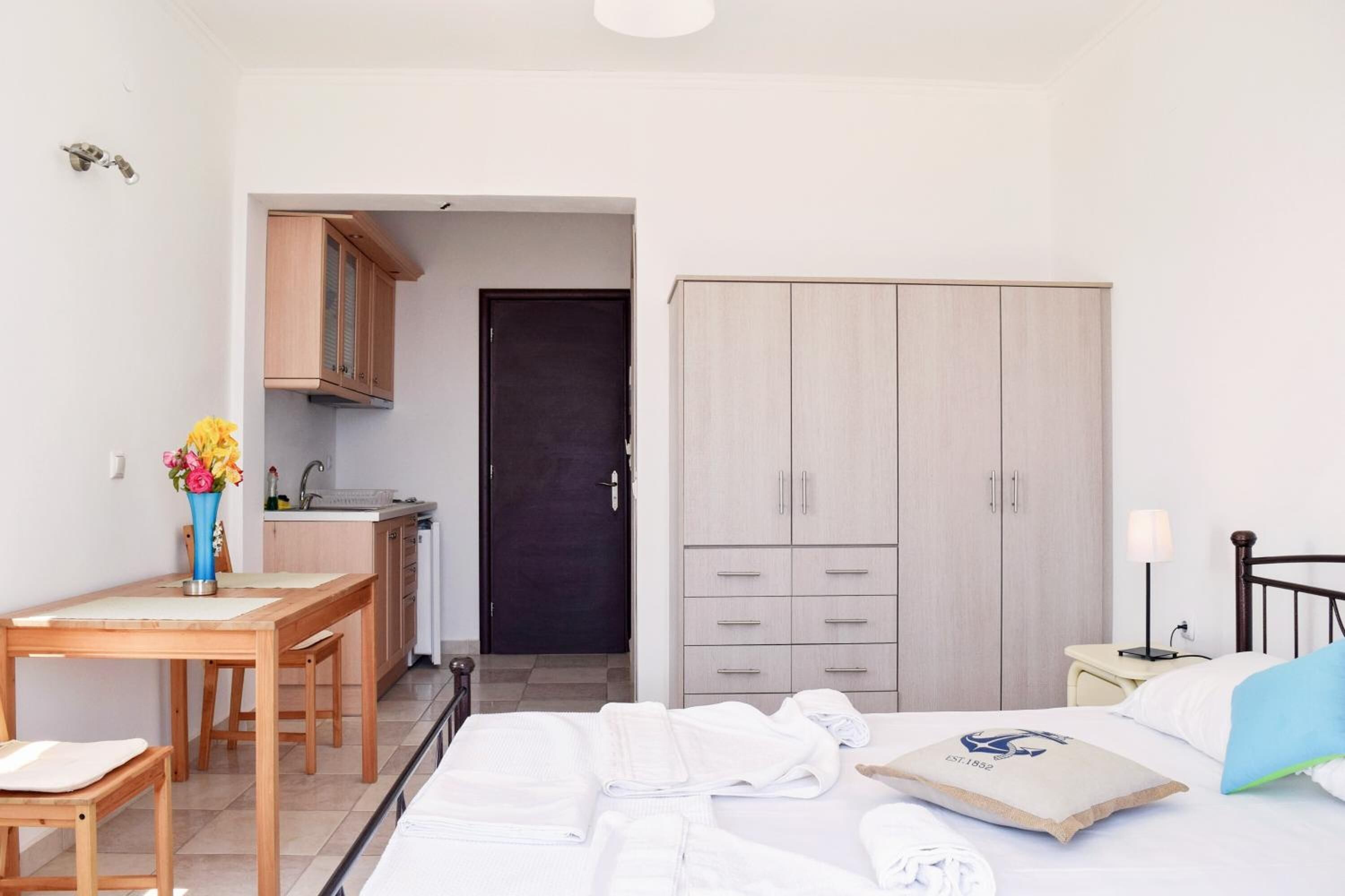 A hotel room with a bed, a desk, a wardrobe, and a small kitchenette.