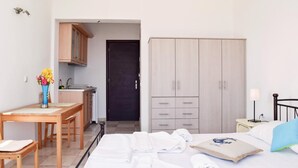 A hotel room with a bed, a desk, a wardrobe, and a small kitchenette.