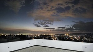 Eine Dachterrasse mit Blick auf die Stadtlandschaft im Abendrot.
