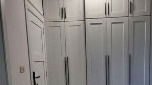 Ein Zimmer mit weißen Schränken, einem Boden im Marmor-Look und Einbauleuchten.
