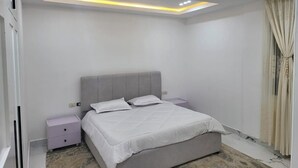 Ein modernes Schlafzimmer mit einem großen Bett, einem Nachttisch und einer Deckenleuchte.