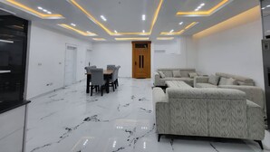 Ein modernes Wohnzimmer mit Marmorboden, einer Couch und einem Essbereich mit Stühlen.