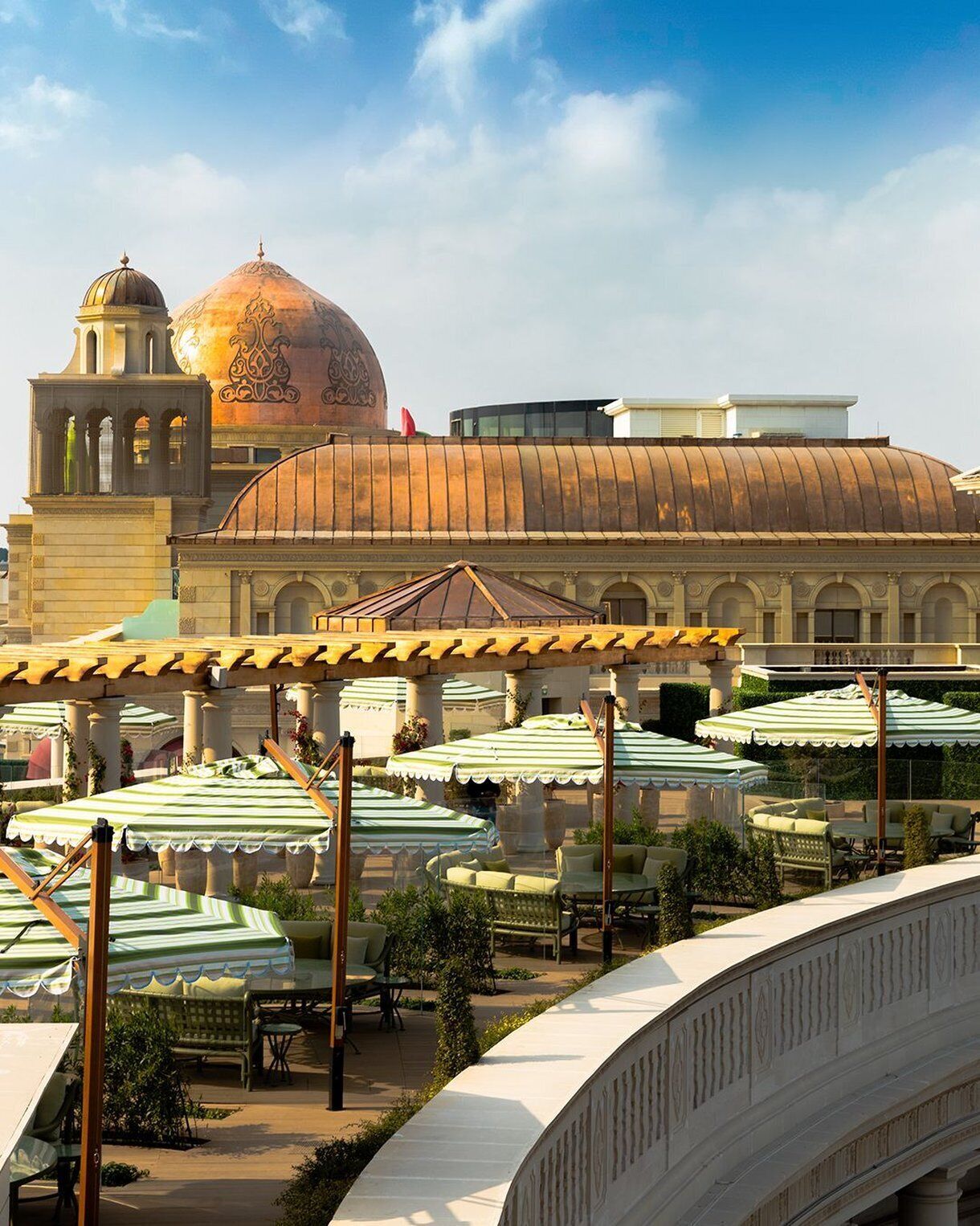 A building with a large dome and a bell tower, surrounded by outdoor seating with umbrellas.