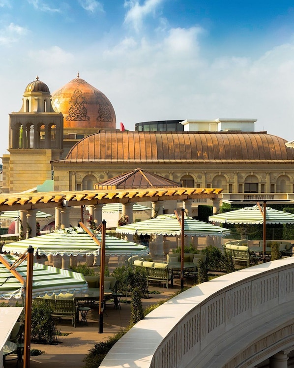 A building with a large dome and a bell tower, surrounded by outdoor seating with umbrellas. - 21 High Street Residence (Doha)
