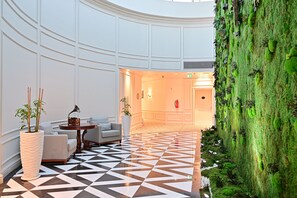 A lobby with a geometric patterned floor, a reception desk, seating area, and a green moss wall. - 21 High Street Residence (Doha)