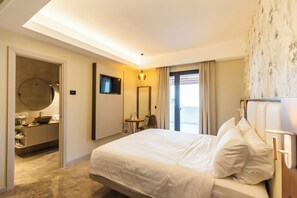 A hotel room with a large bed, a round mirror, a television, and a bathroom with a sink and toilet. - Solmaris Tropea Rooms & Suites (Tropea)