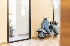 A blue vintage scooter parked indoors, near a glass door leading to a balcony with a potted plant. - Solmaris Tropea Rooms & Suites (Tropea)
