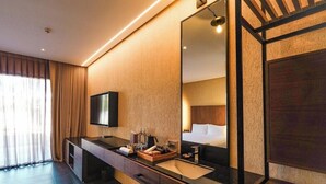 Ein modernes Badezimmer mit einem großen Spiegel, einem Waschbecken und einem Fernseher.