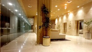A spacious lobby with a polished marble floor, wooden panel ceiling, and a seating area with a sofa and armchairs. - LK Hotel Chadstone Cikarang (Cikarang)