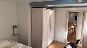 Ein Schlafzimmer mit Bett, Kleiderschrank, Lampe und einem Flur, der in einen Essbereich führt.