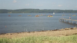 Een rustig meer met bootjes, een pier en een lichtbaken in de verte.
