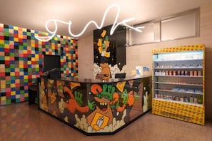 A colorful reception area with a cartoon character design, a neon sign, and a beverage vending machine. - Far East Village Hotel Osaka, Honmachi (Osaka)