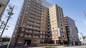 Ein mehrstöckiges Hotel mit modernem Design, das eine Mischung aus Balkonen und Fenstern in jeder Etage zeigt.