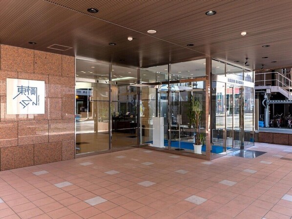 Une entrée moderne avec une porte en verre, une enseigne avec des caractères japonais et un sol carrelé.