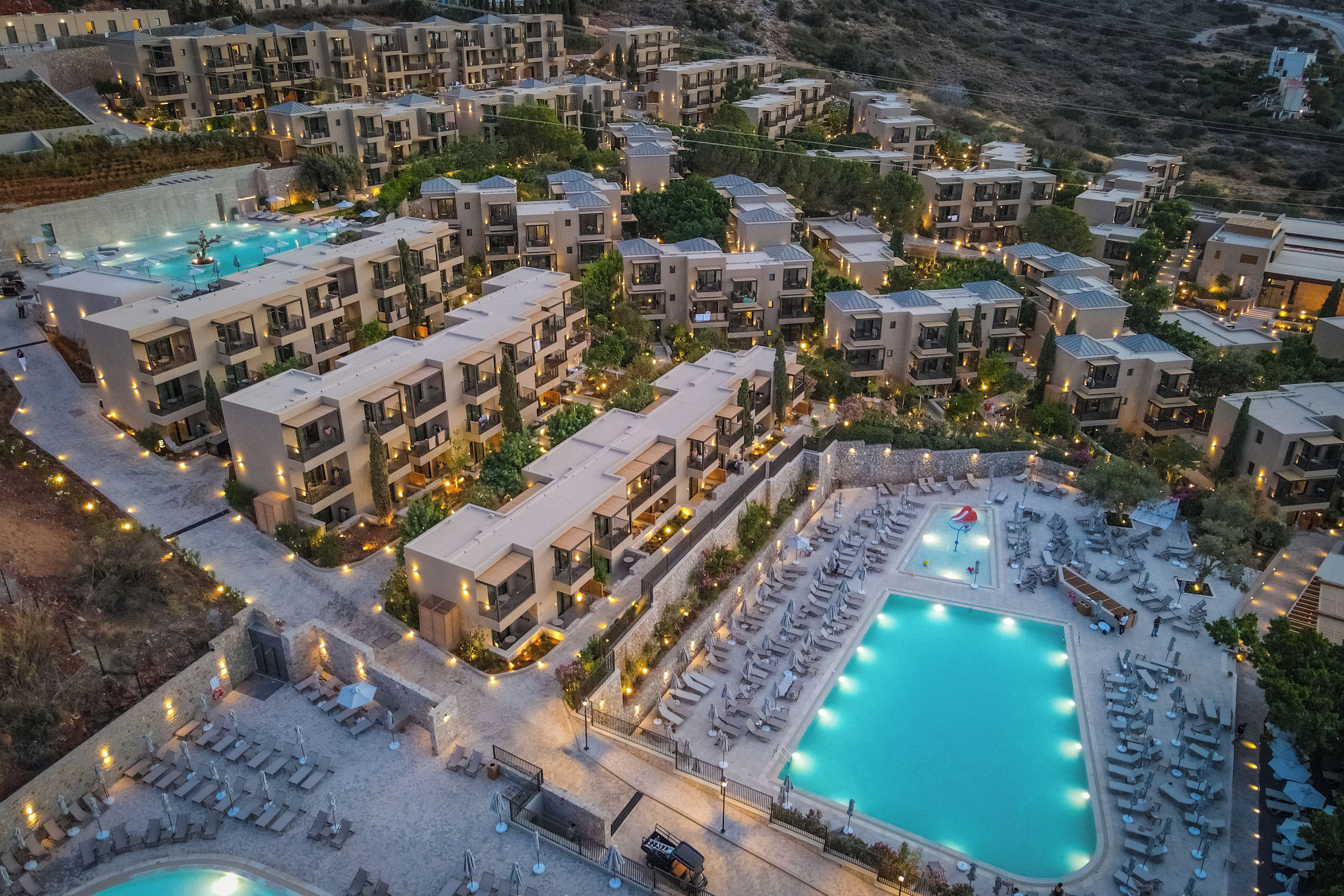 A resort with multiple buildings, a central swimming pool, and outdoor seating areas.