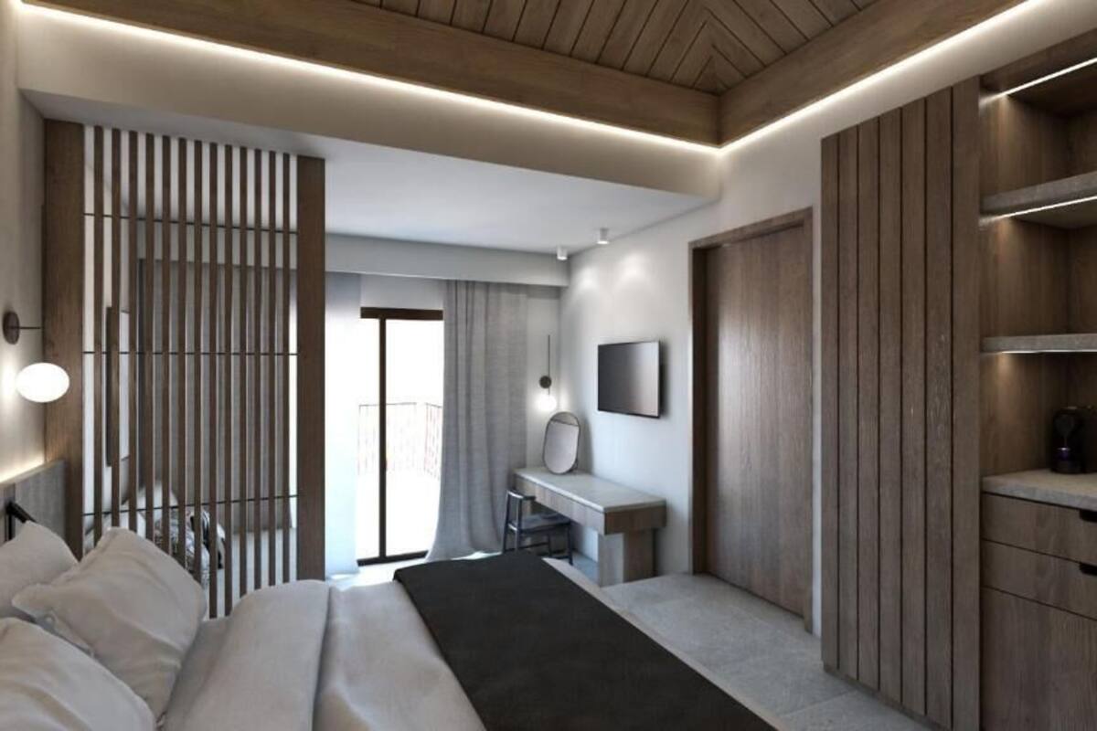 A modern hotel room with a bed, desk, and wardrobe.