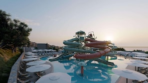A water park with slides, a pool, and lounge chairs. - Elios Hill (Hersonissos)