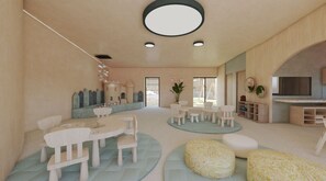 A spacious living area with a round table, chairs, and a play area with a castle-like structure.