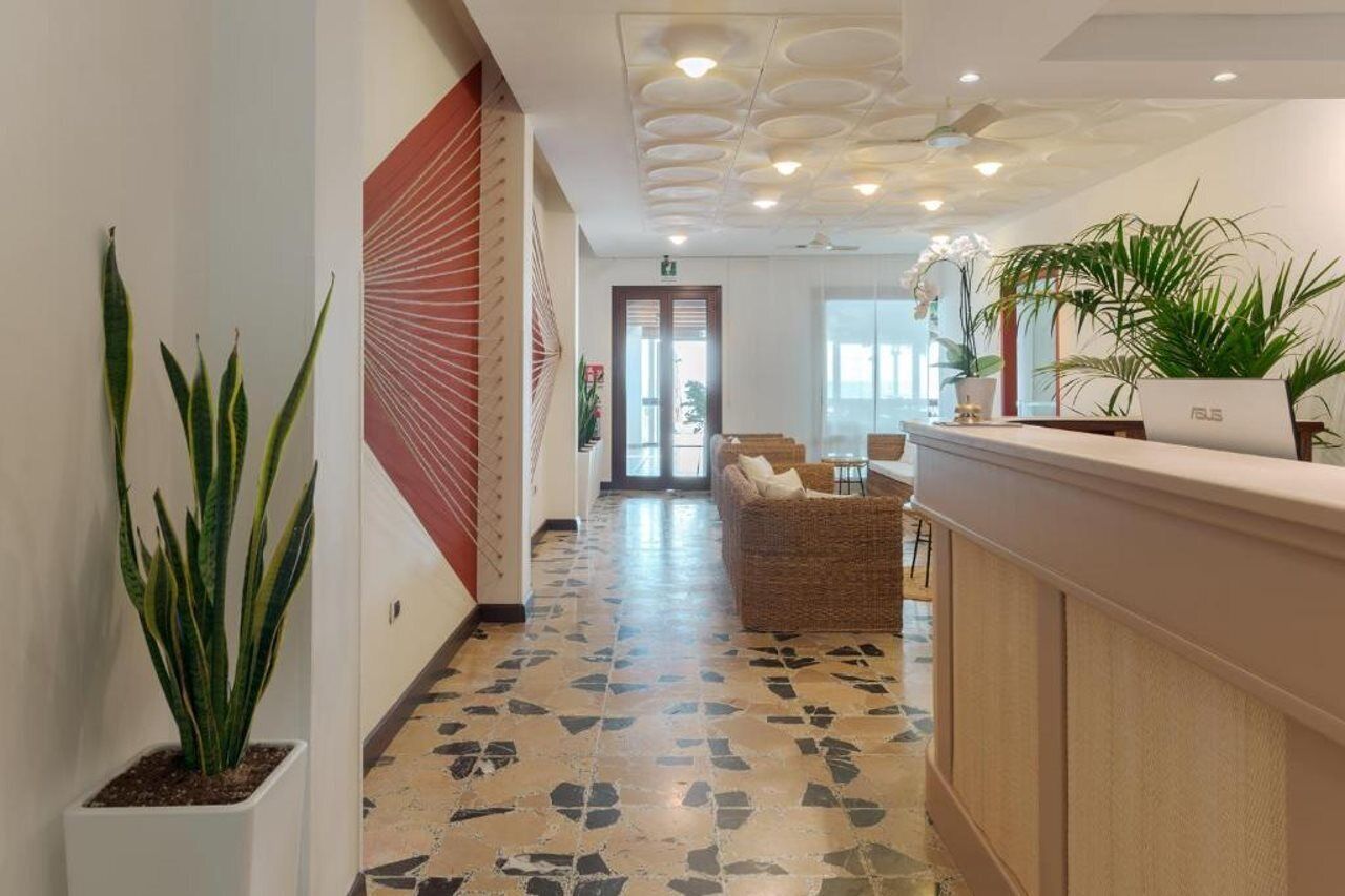 A hotel lobby with a reception desk, a seating area, and a patterned floor.