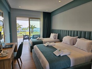 A hotel room with two beds, a desk with a laptop, and a view of the ocean. - Sea Coast Resort (Polygyros)